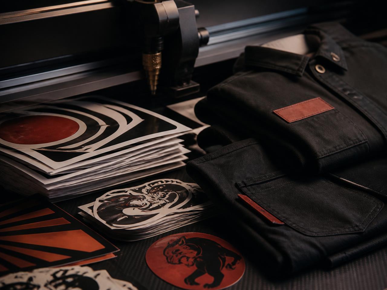 Cut vinyl stickers and decals stacked beside a plotter and folded workwear